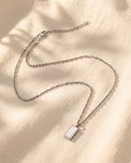 Marco Maveri Rectangular Bar Pendant Necklace laid on cream linen, Silver