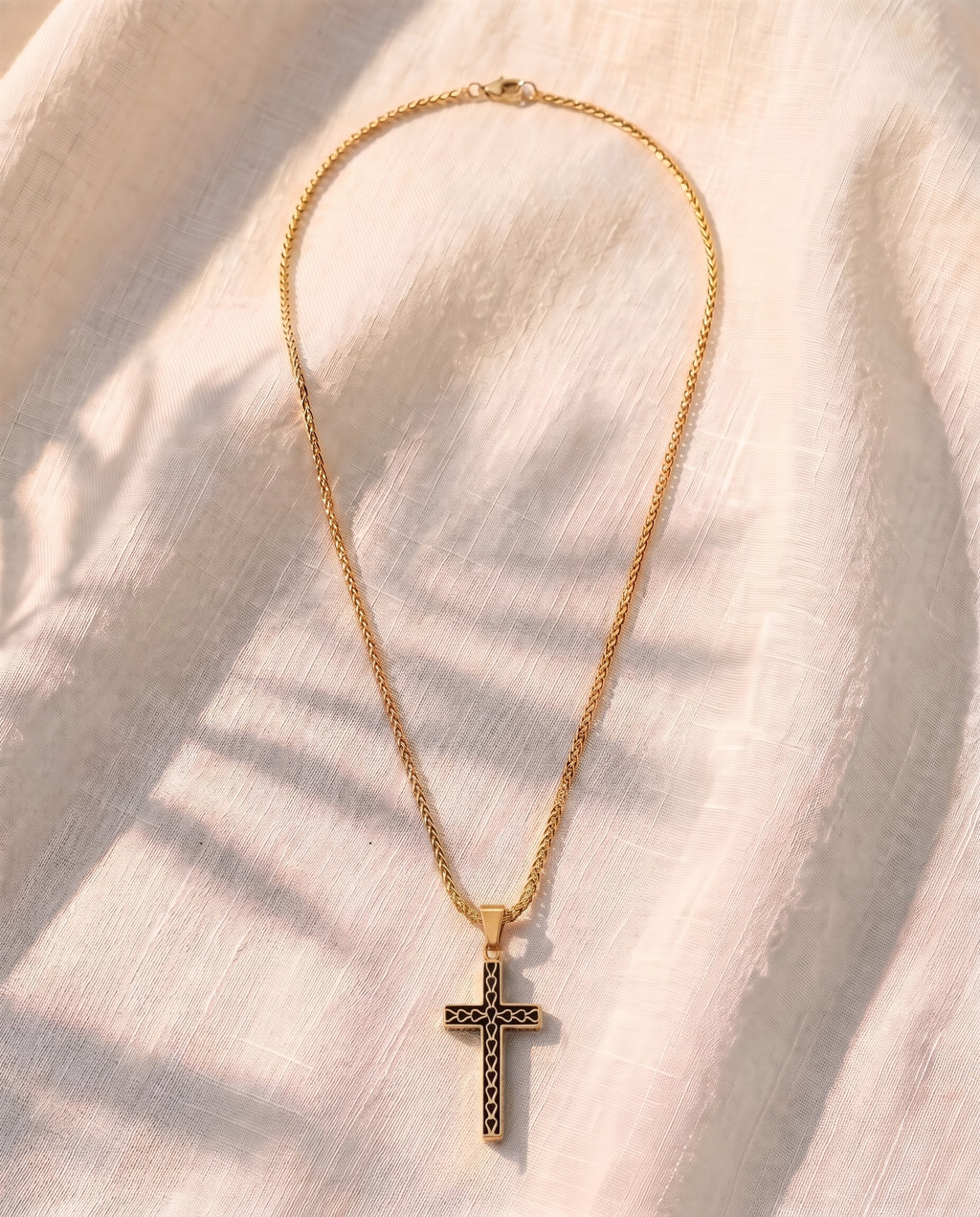 Marco Maveri Textured Cross Pendant Necklace laid on cream linen, Gold