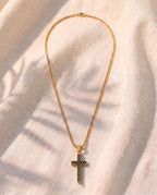 Marco Maveri Textured Cross Pendant Necklace laid on cream linen, Gold