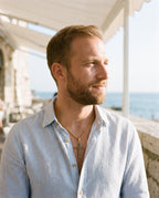 Man wearing the Marco Maveri Textured Cross Pendant Necklace by the sea, Gold