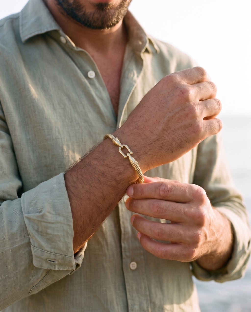 Man adjusting the Marco Maveri Twisted Steel Hook Bangle, close-up, Gold