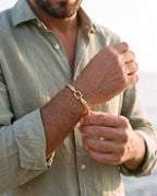 Man adjusting the Marco Maveri Twisted Steel Hook Bangle, close-up, Gold