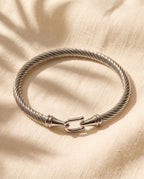 Marco Maveri Twisted Steel Hook Bangle laid on cream linen, Silver