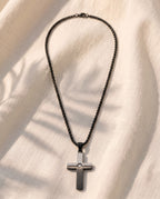 Marco Maveri Two-Tone Inlaid Cross Pendant Necklace laid on cream linen, Black / Silver