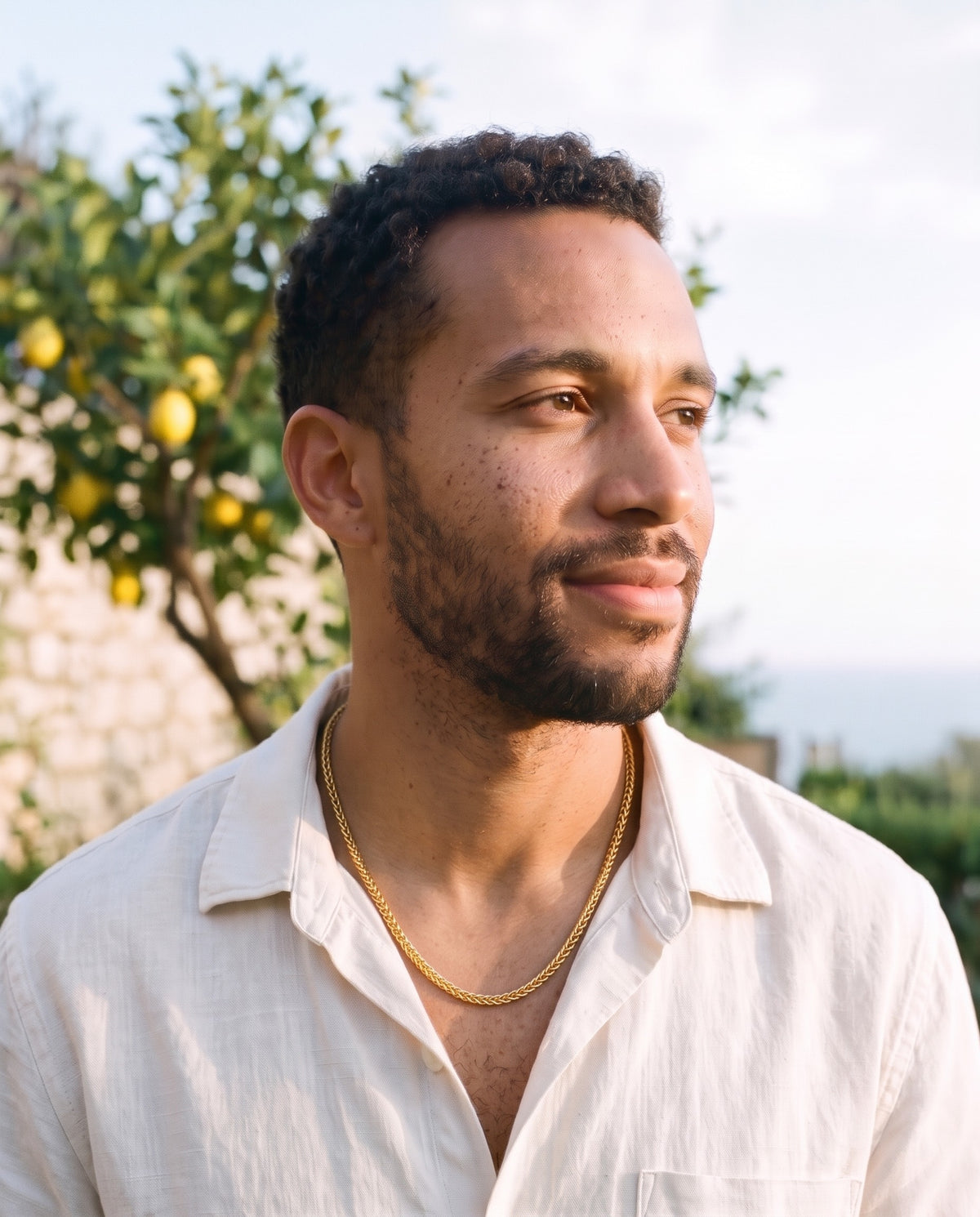 Man wearing the Marco Maveri Wheat Link Chain in Titanium Steel by the sea, Gold