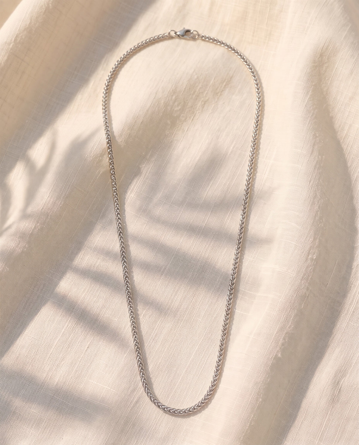 Marco Maveri Wheat Link Chain in Titanium Steel laid on cream linen, Silver